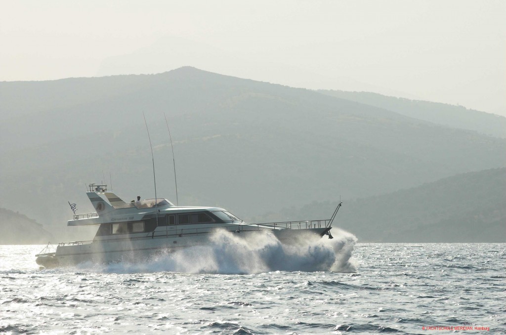 Große Motoryacht fährt durch eine Welle in schneller Fahrt.